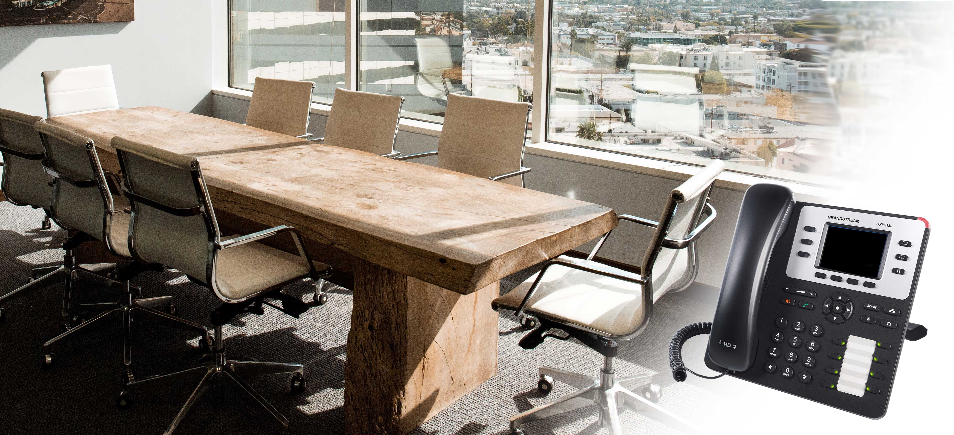 A voip phone sitting to the left of a common boardroom table